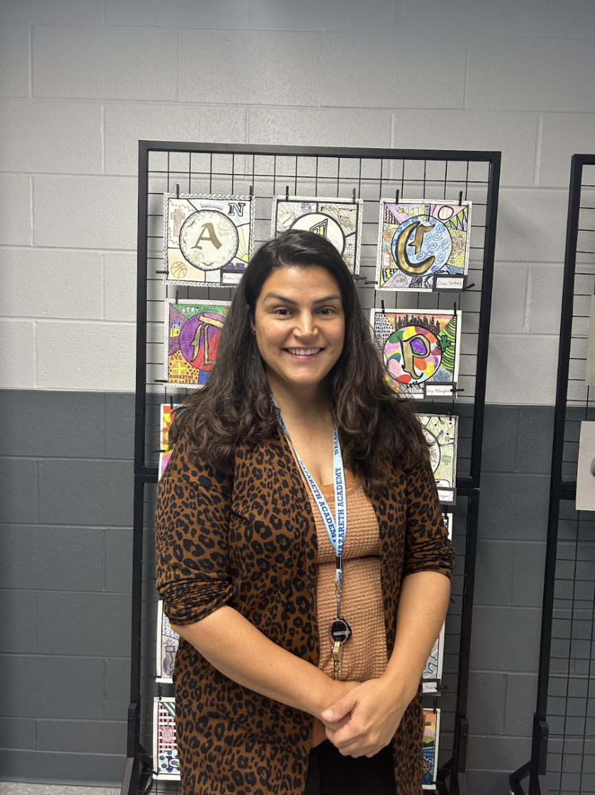 Kueker in front of a display of student artwork.