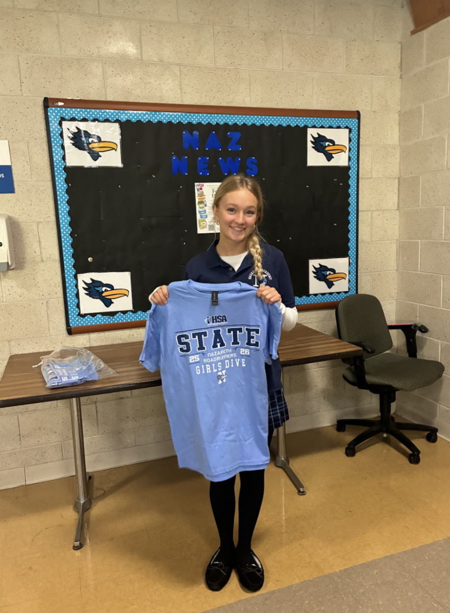 Fleischmann holding up her state tee in the lunchroom before heading to the competition. 